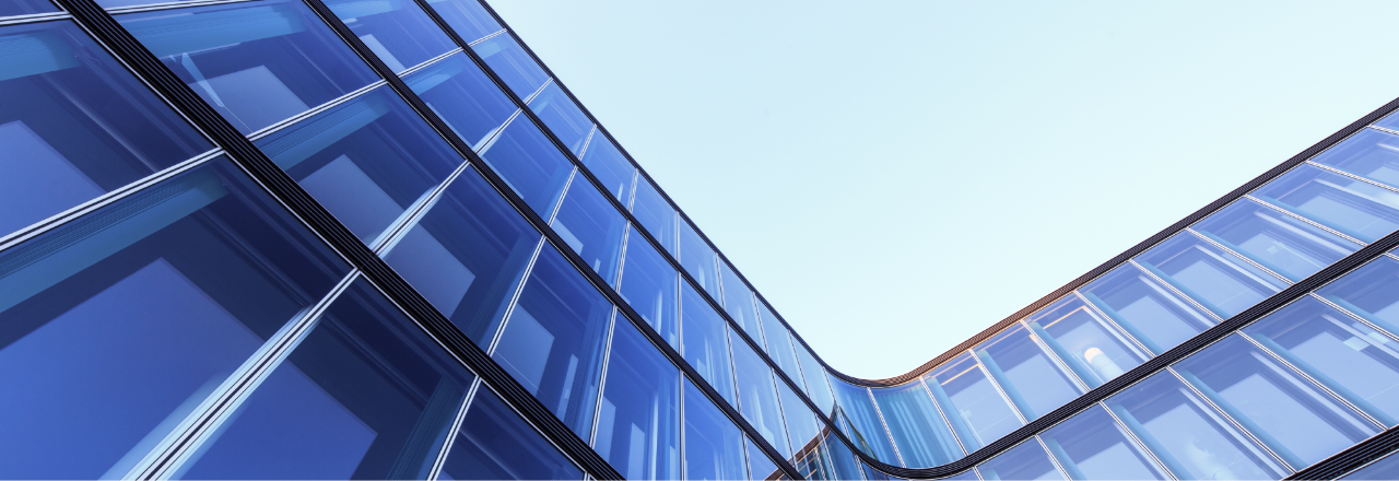 Photograph of the side of a glass building and the sky looking up